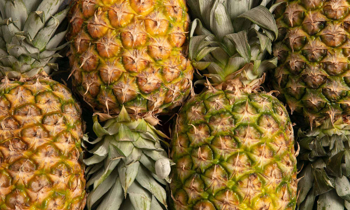 Viele frische Ananas Fruechte neben und aufeinander