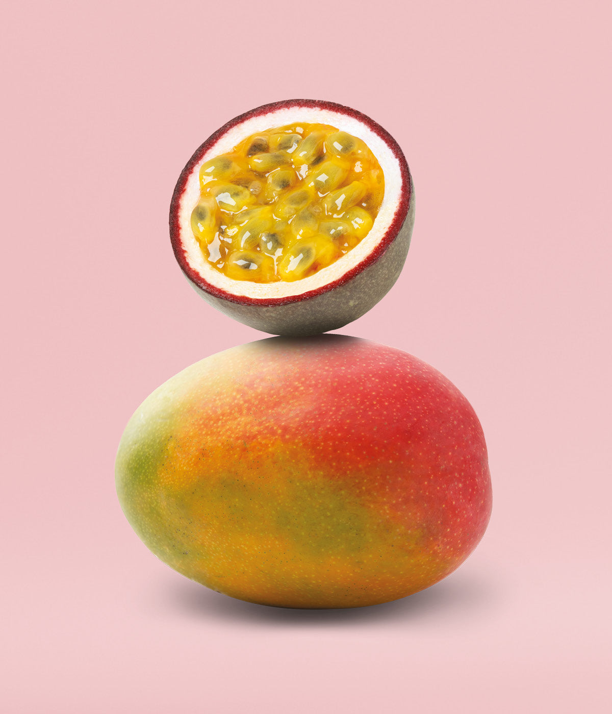 Aufgeschnittene, frische Maracuja liegt auf einer reifen, orangenen Mango vor rosa Hintergrund