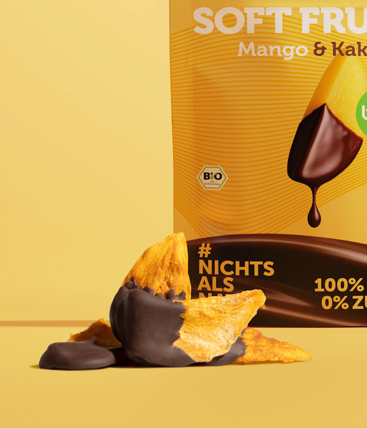 Getrocknete Bio-Mangostücke mit dunklem Kakaomantel vor der buah Soft Fruits Mango & Kakao Verpackung