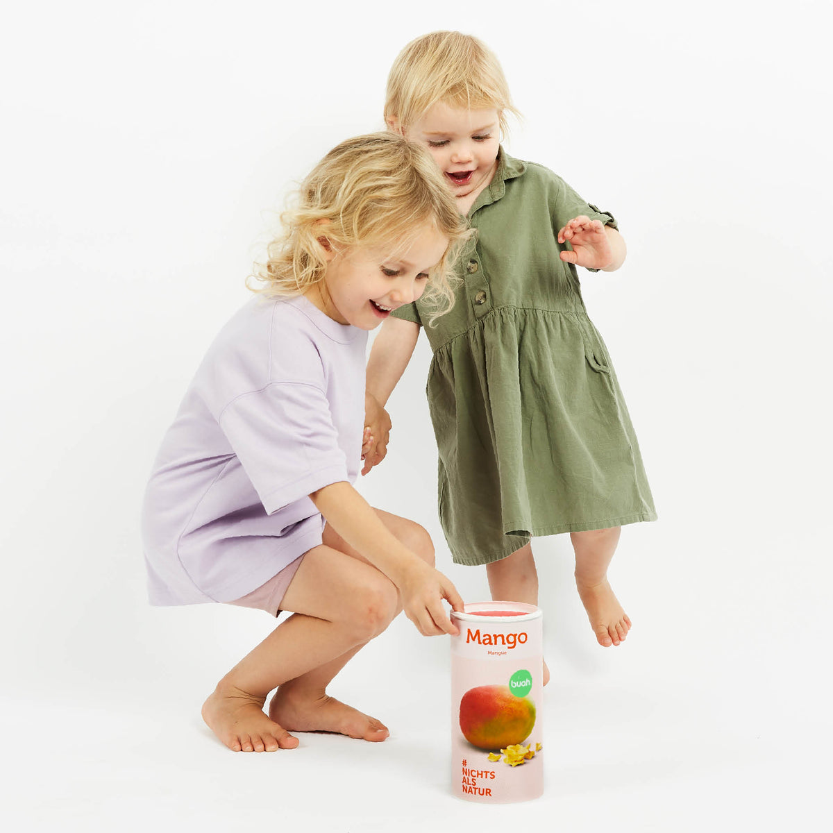 Zwei kleine Kinder lachen und greifen nach einer Dose buah gefriergetrocknete Mango