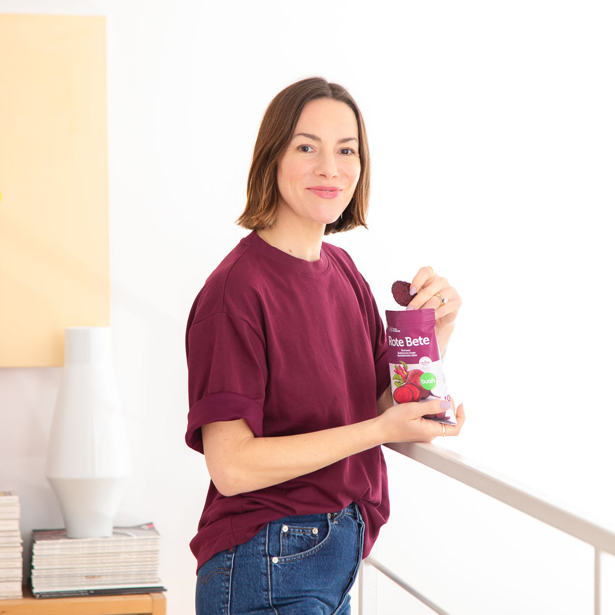 Frau in lila Shirt lacht in Kamera und isst buah Rote Bete Chips