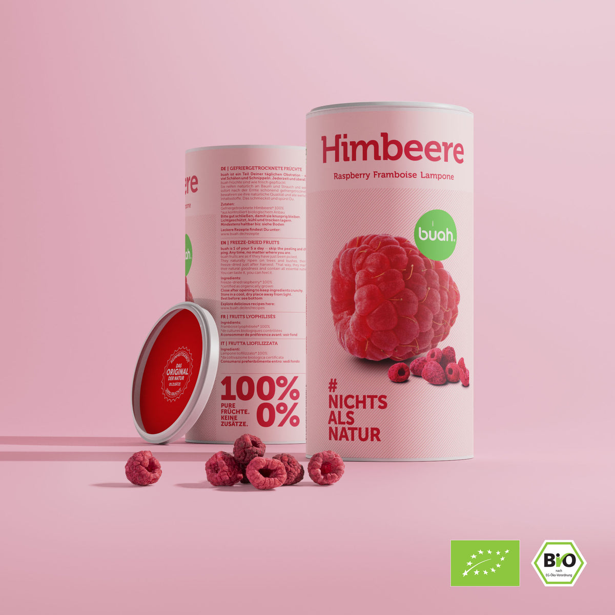 Zwei Dosen buah Himbeeren stehen nebeneinander mit einem kleinen Haufen gefriergetrockneter Himbeeren im Vordergrund