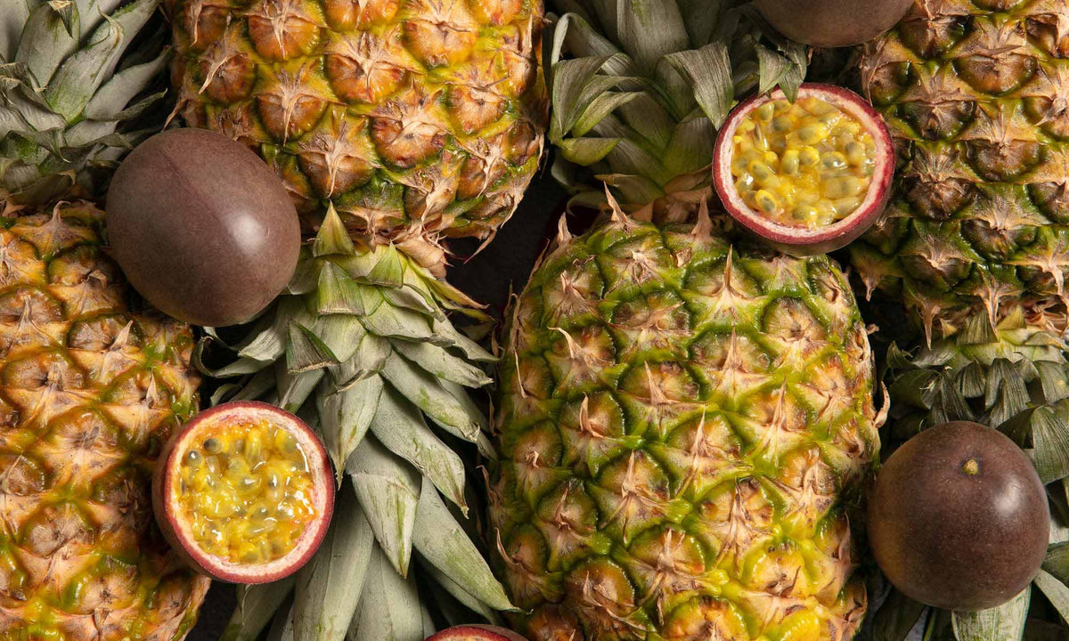 Viele halbierte Maracuja und ganze Ananas liegen neben und aufeinander