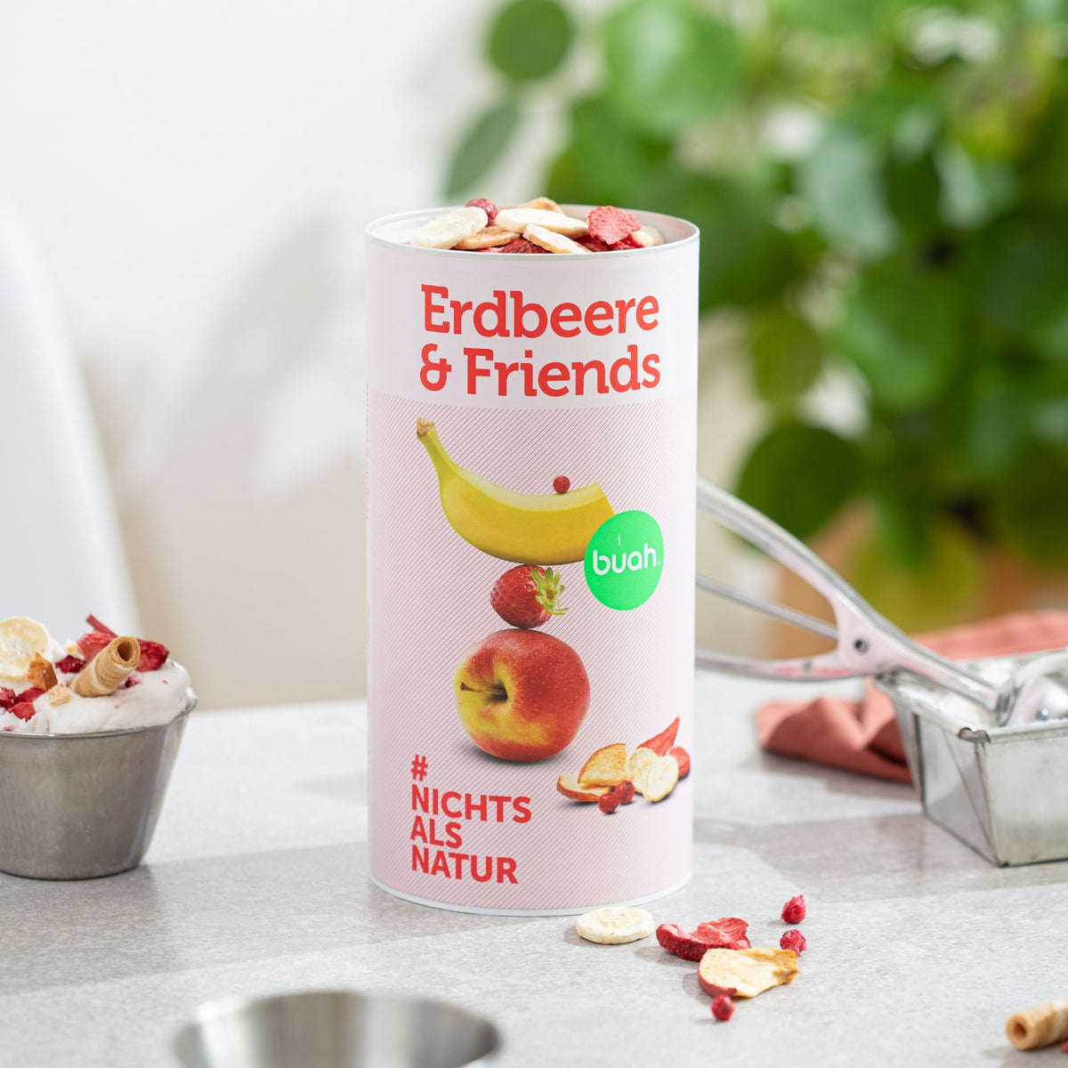 buah Dose Erdbeere & Friends steht auf einem Tisch neben einem Eisbecher 