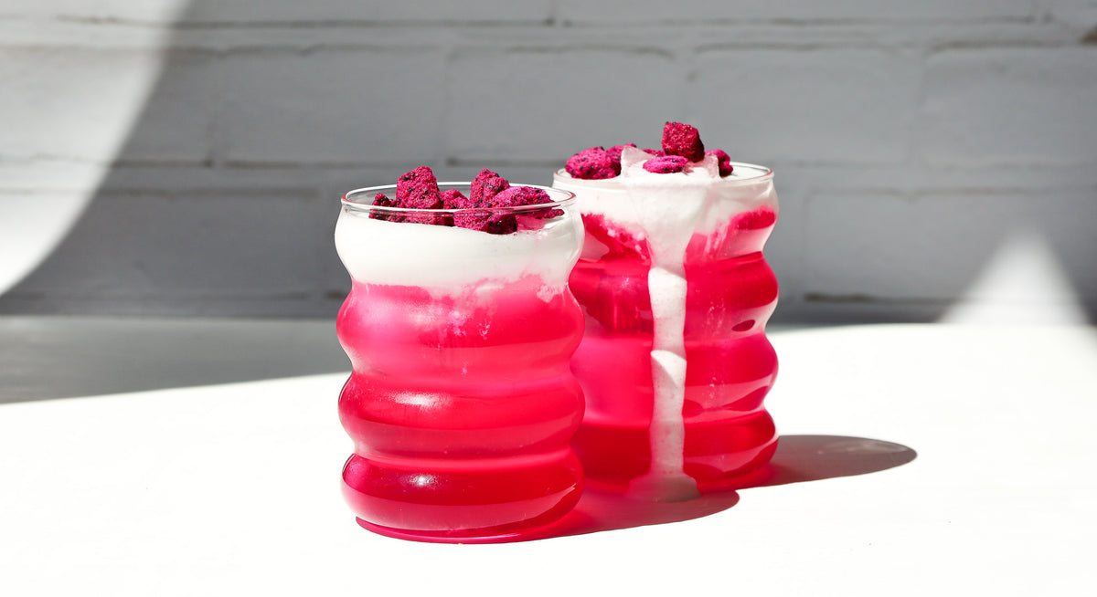 Zwei Bubble Gläser gefuellt mit pinker Limonade und Cold Foam on top, garniert mit buah gefriergetrockneter Drachenfrucht