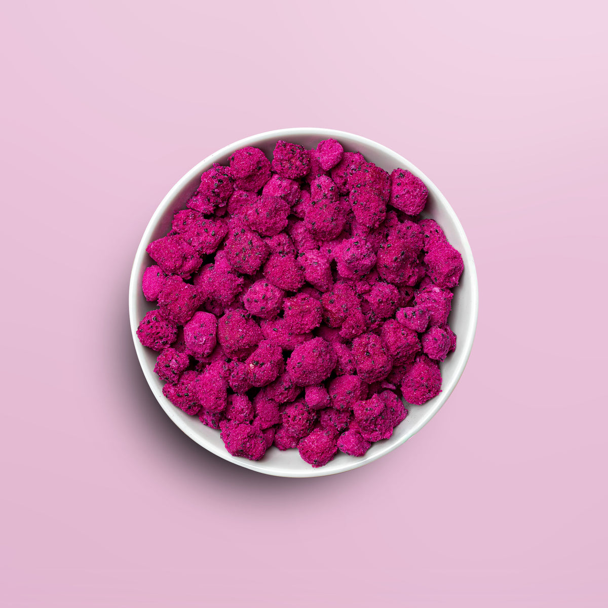 Weisse Schale mit buah gefriergetrockneter Drachenfrucht in sattem pink vor rosa Hintergrund