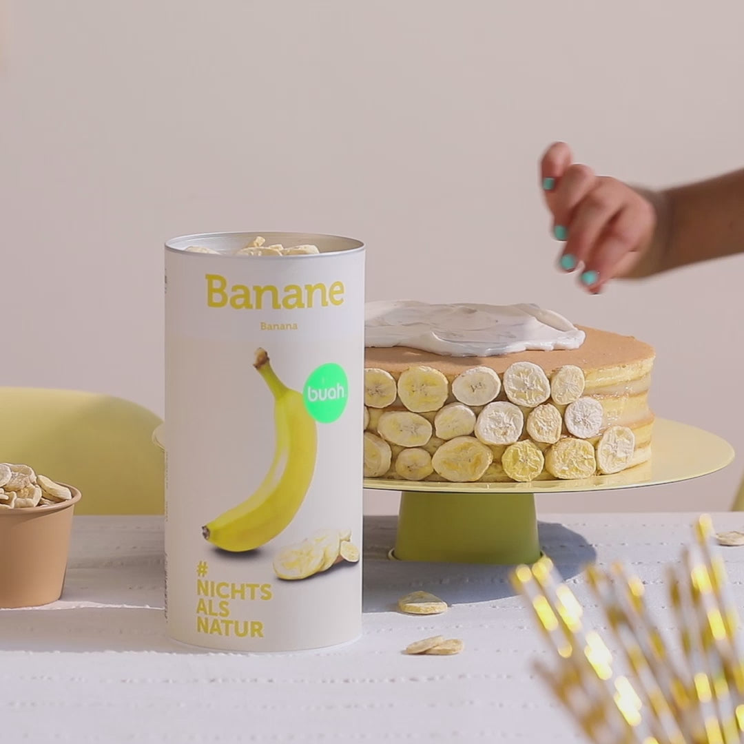 Hand greift in eine Schale mit buah gefriergetrockneter Banane und nimmt einen Chip heraus