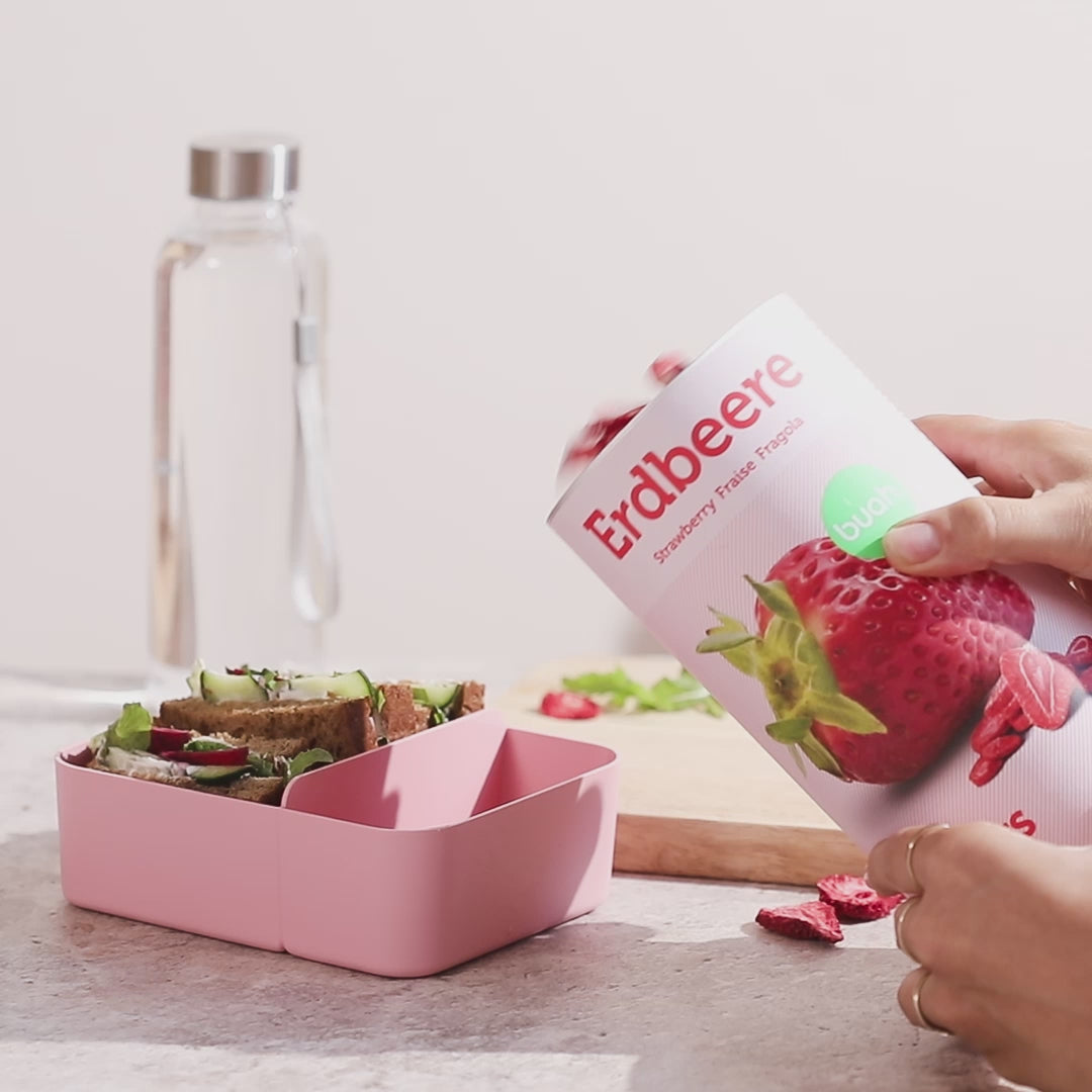 Video, wie buah Erdbeeren in eine rosa Brotdose hinzugegeben werden